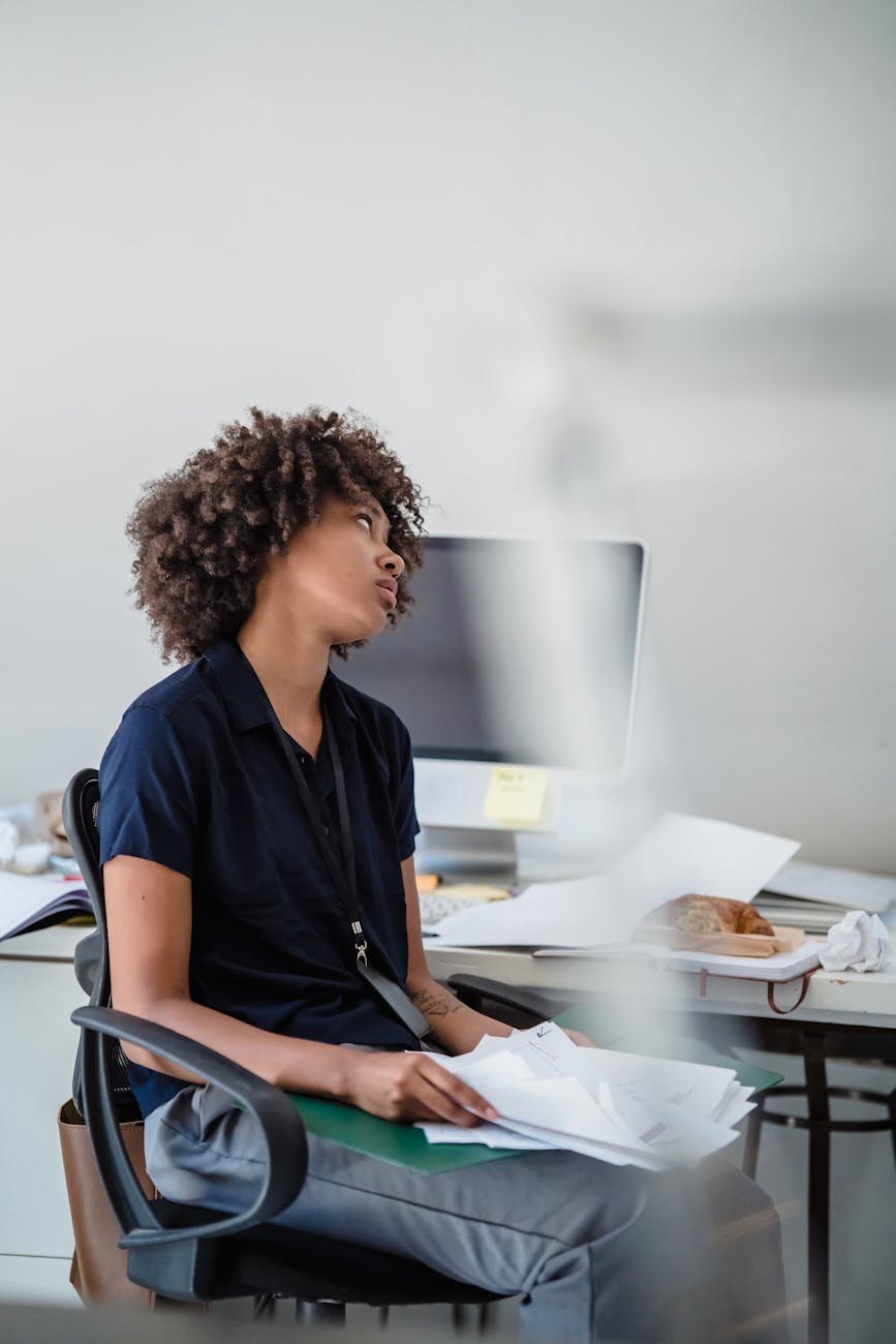 woman sitting at the desk in an office with papers in her lap