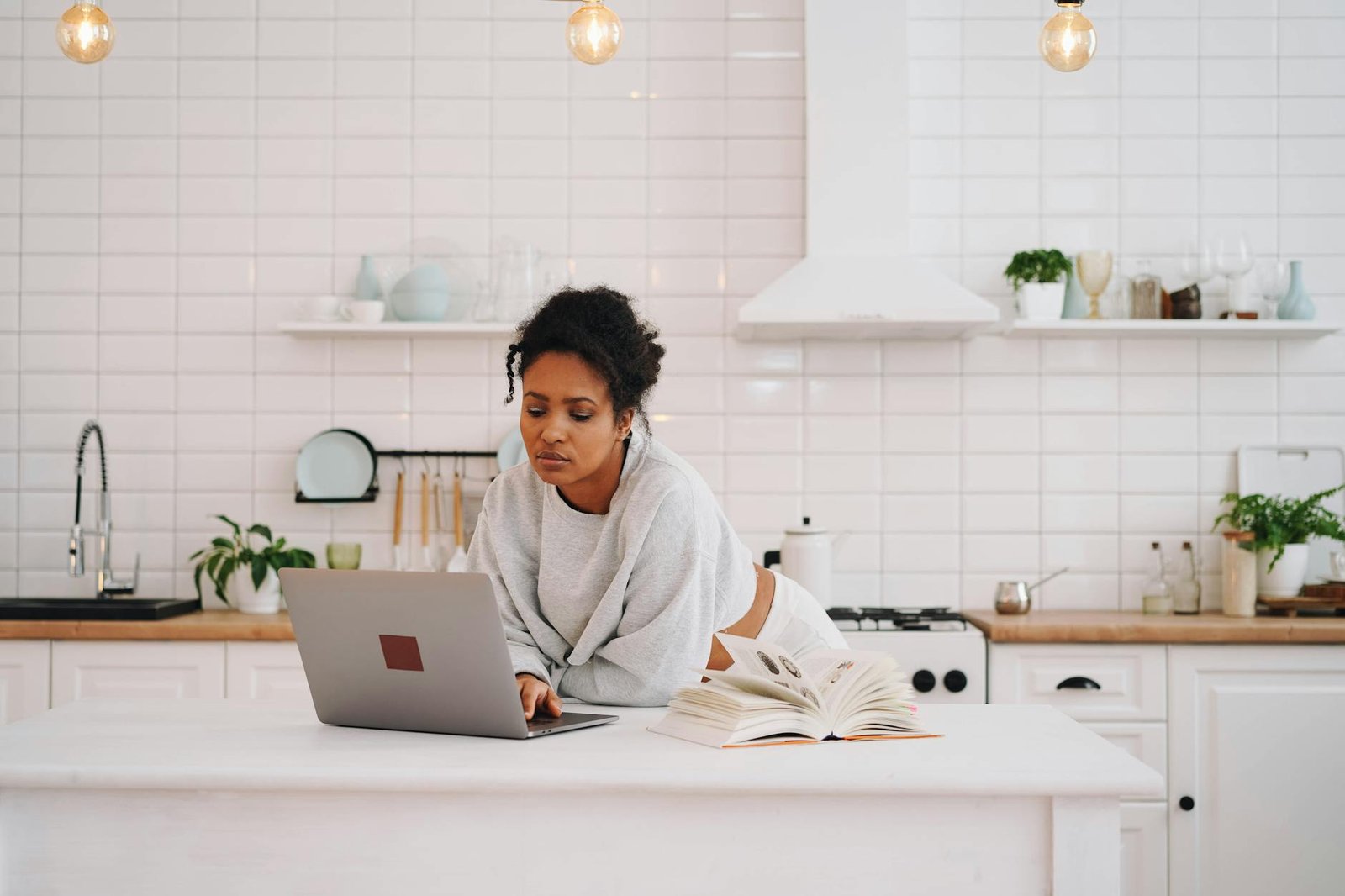 a woman in gray sweater using her laptop in the kitchen